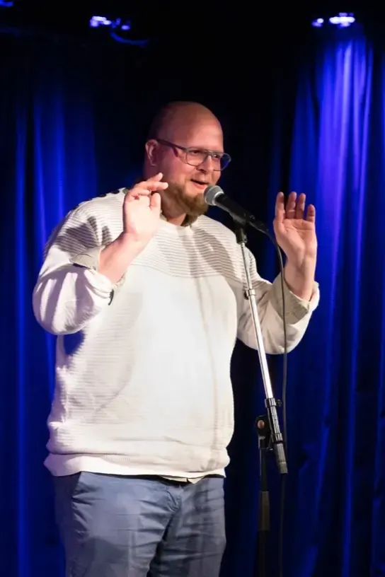 Florian Zejewski mit Mikrofon auf der Bühne
